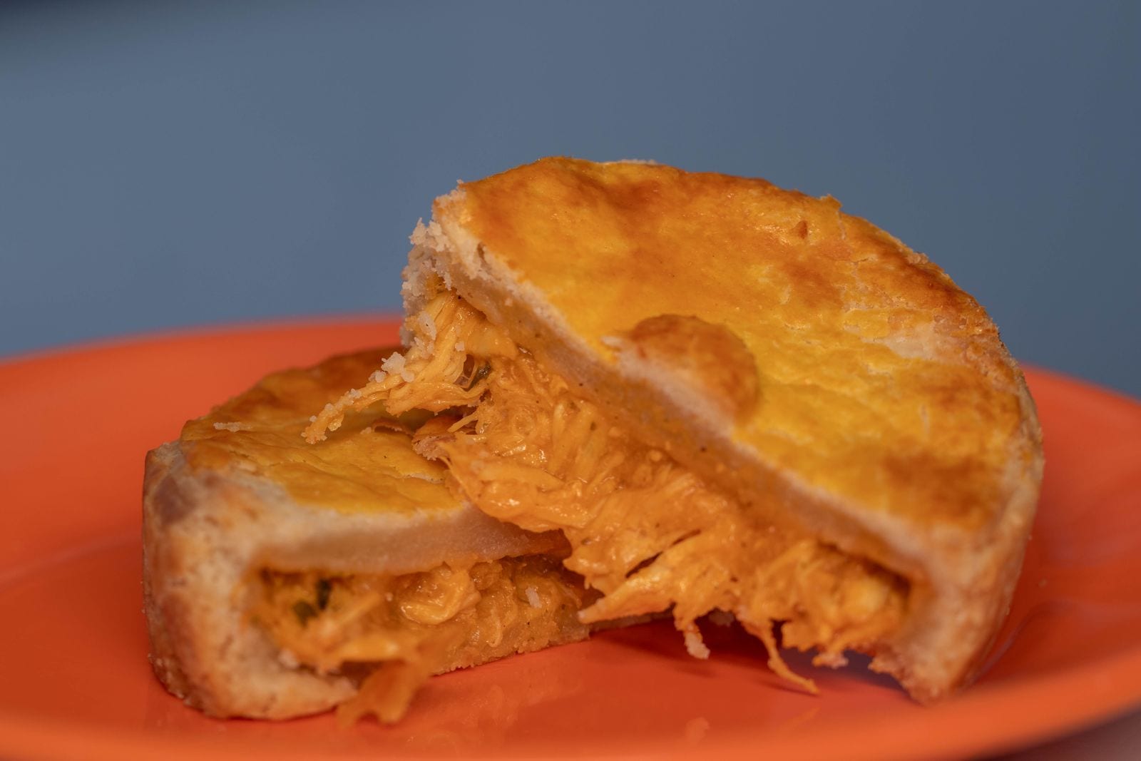 A flaky chicken pie on a bright orange plate