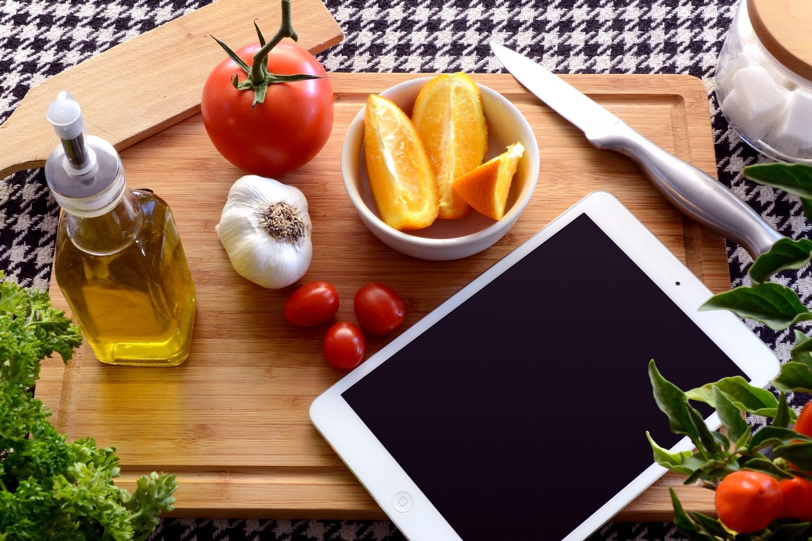 Fresh ingredients and a tablet on a wooden cutting board