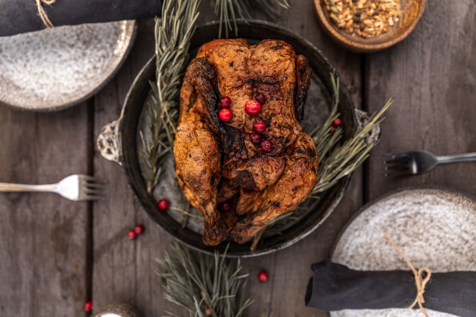 A roasted turkey garnished with cranberries on a wooden table