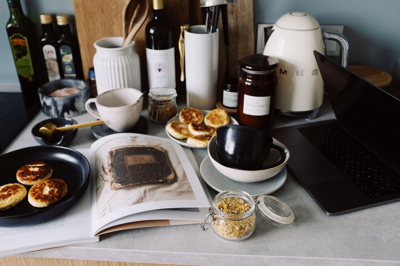Kitchen worktop with utensils, pancakes and an open laptop