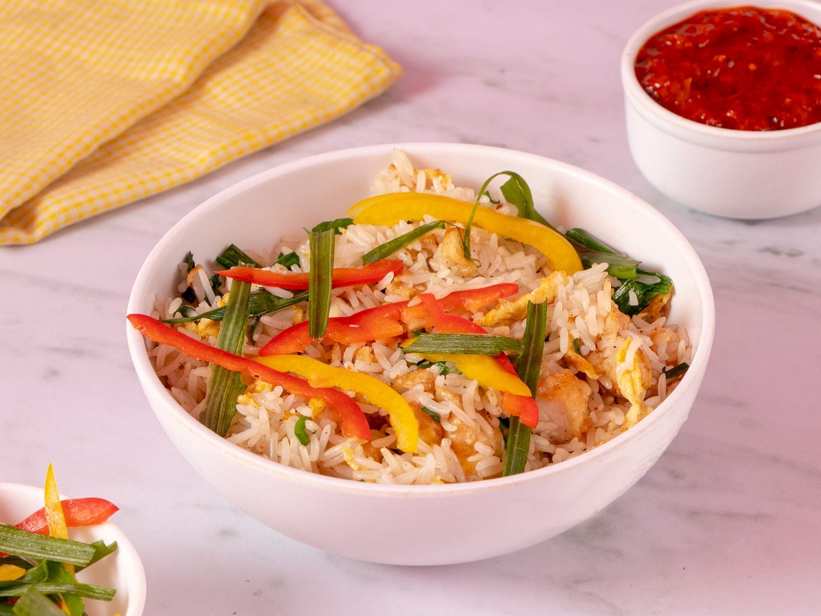 Fried rice topped with colourful bell peppers in a white bowl