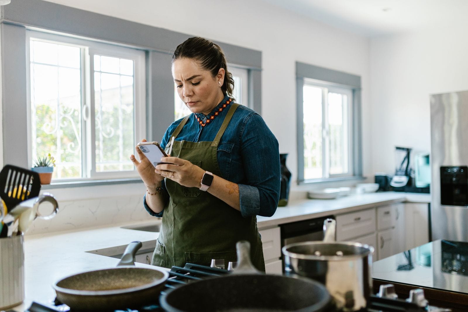 Woman in a modern kitchen following a recipe on her smartphone