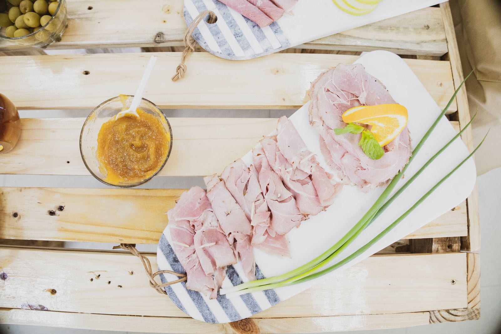 Slices of ham with an orange garnish on a rustic board