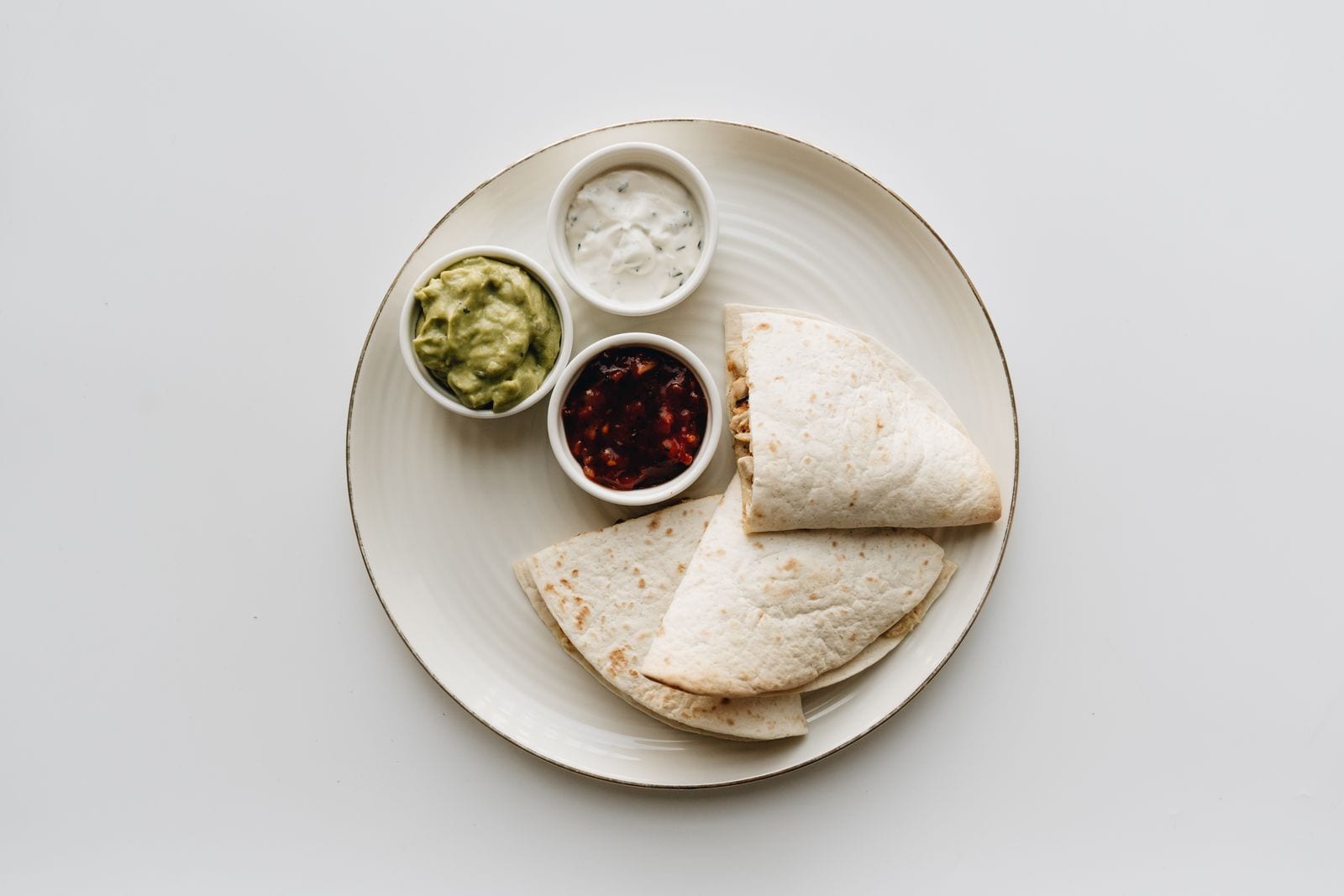 A Mexican quesadilla served with guacamole, salsa and sour cream